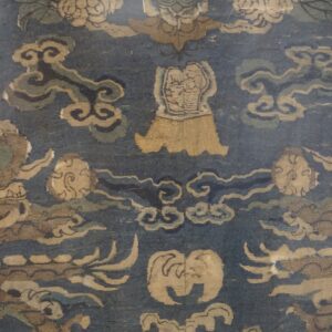 Close-up of a low-pile blue rug featuring traditional tan and muted green dragon and cloud patterns.