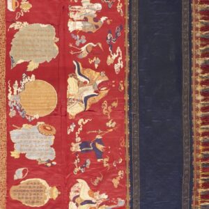 Shiny red textile featuring embroidered figures and script is bordered by blue fabric and elaborate fringe.