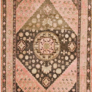 Geometric rug featuring a concentric diamond and medallion design in faded pink, brown, and taupe.