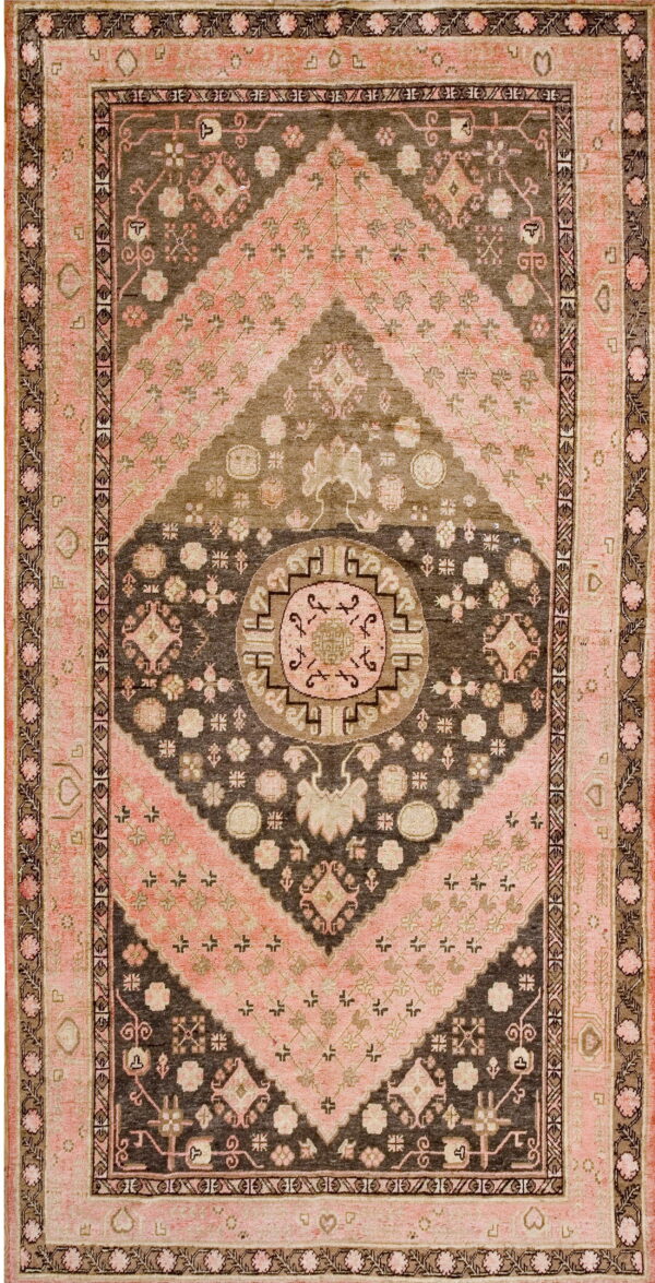 Geometric rug featuring a concentric diamond and medallion design in faded pink, brown, and taupe.