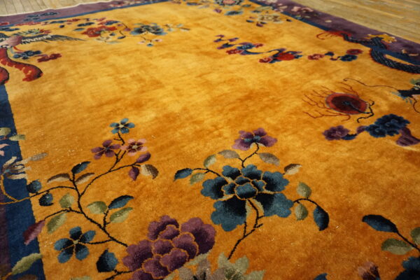Deep gold high-pile rug featuring blue, purple, and red floral designs and stylized animal figures.