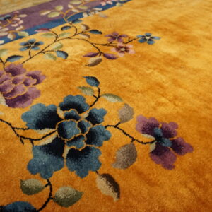Gold rug with a plush pile and a detailed traditional floral pattern in blue and purple.