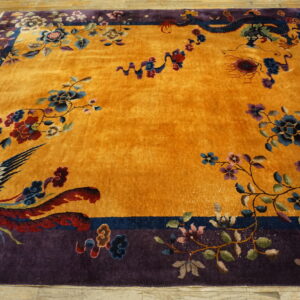 Ornate yellow rug with a purple border patterned with a stylized bird, dragon, and colorful flowers.