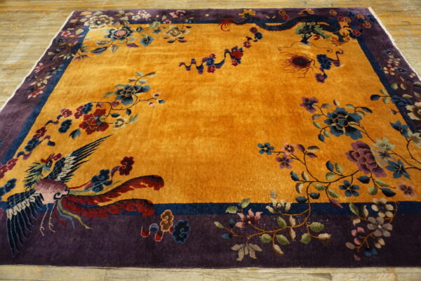 Ornate yellow rug with a purple border patterned with a stylized bird, dragon, and colorful flowers.