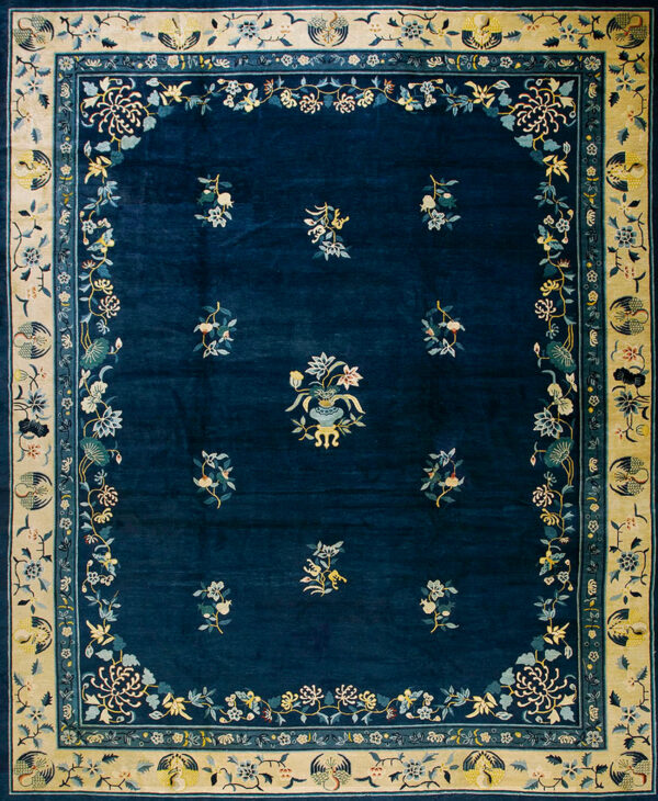 Deep blue rug featuring scattered pale floral motifs and a wide beige border with detailed medallions.