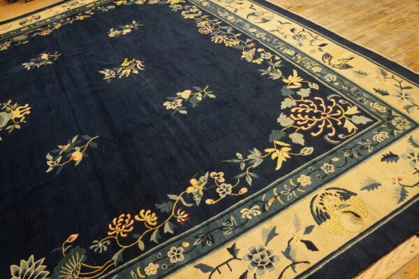 Navy blue rug with scattered yellow floral sprigs and a cream border featuring teal designs on wood flooring.