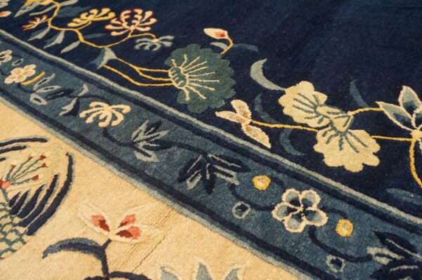Detail shot of a rug with navy blue, beige, and teal borders framing stylized yellow and green floral patterns.
