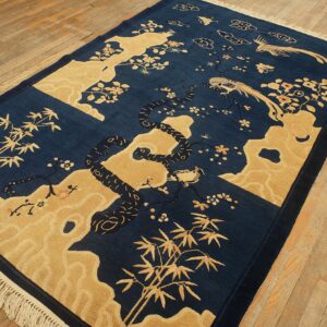 Dark indigo and gold scenic rug showing bamboo, birds, and flowering branches on a hardwood floor.