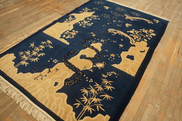 Dark indigo and gold scenic rug showing bamboo, birds, and flowering branches on a hardwood floor.