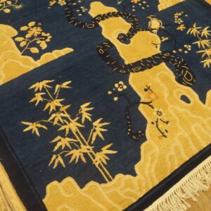 Blue and gold textured rug featuring a coiled snake, bamboo, and flowers on hardwood floors.