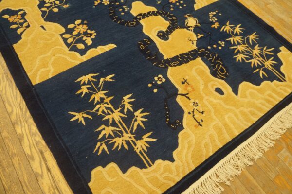Blue and gold textured rug featuring a coiled snake, bamboo, and flowers on hardwood floors.