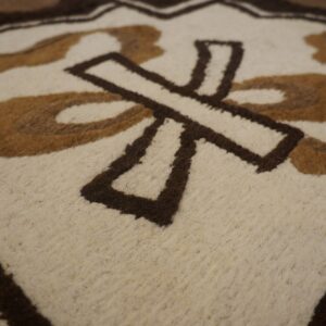Low-pile rug detail showing cream, tan, and dark brown abstract geometric shapes.