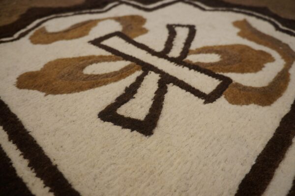 Low-pile rug detail showing cream, tan, and dark brown abstract geometric shapes.