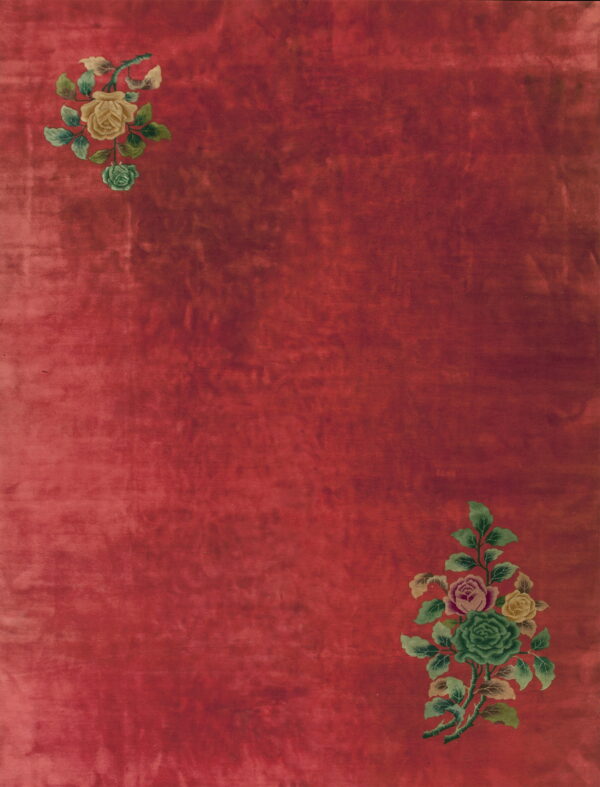 Red rug with low pile featuring floral clusters of yellow, green, and pink in diagonal corners.