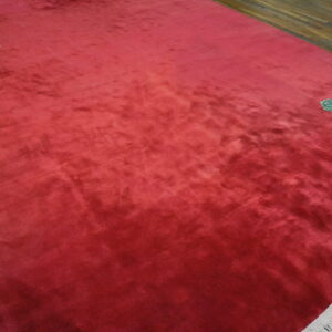 Textured magenta rug on wood floor with corner floral patterns of yellow, green, and pink roses.