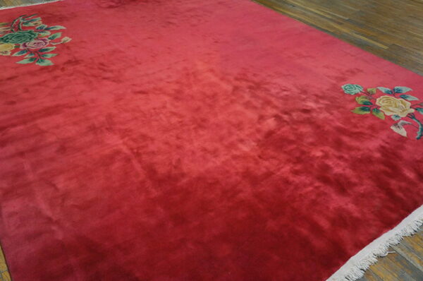 Textured magenta rug on wood floor with corner floral patterns of yellow, green, and pink roses.