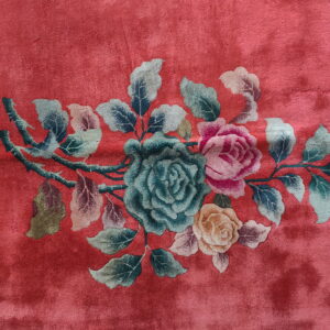 High pile rug in deep rose features a floral motif with teal, pink, and yellow roses.