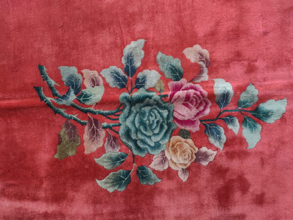 High pile rug in deep rose features a floral motif with teal, pink, and yellow roses.