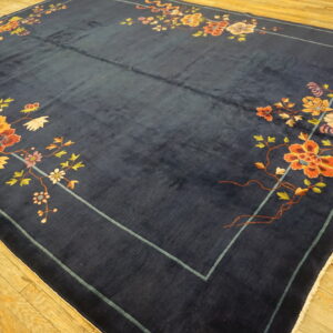Navy rug with visible high pile and multicolor floral vines laid on light-toned hardwood floor.