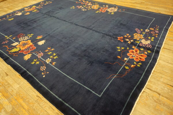 Navy rug with visible high pile and multicolor floral vines laid on light-toned hardwood floor.