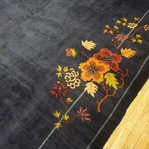 Velvety dark blue rug featuring large autumn-toned floral vines and a striped border on light wood flooring.