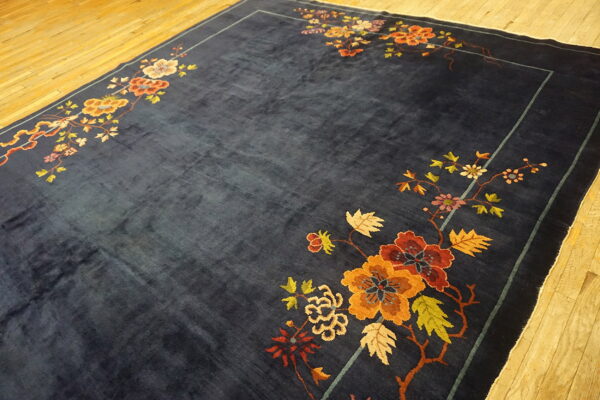 Deep blue rug with bright floral corner motifs in rust, gold, and green on a polished wood floor.