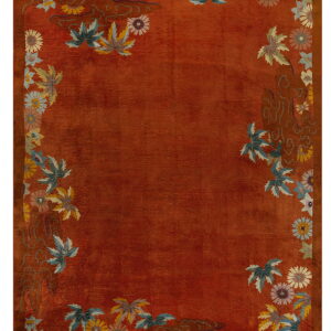 Terracotta rug with an ornamental border of multicolored flowers, leaves, and stylized swirling motifs.