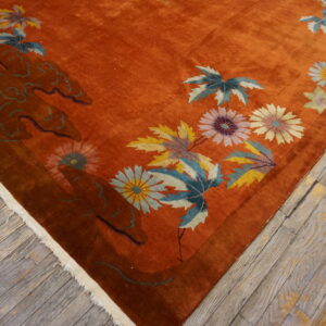 Velvety rust-colored rug with bold yellow, blue, and pink floral patterns on distressed wood.