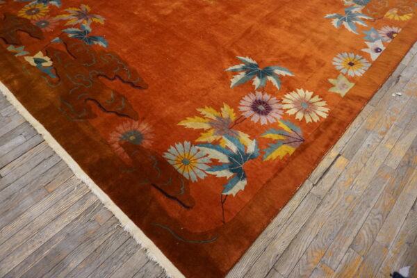Velvety rust-colored rug with bold yellow, blue, and pink floral patterns on distressed wood.