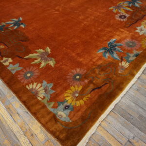 Rust-colored high-pile rug featuring yellow, blue, and green floral motifs on distressed wooden flooring.