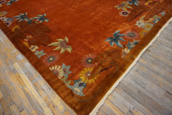 Rust-colored high-pile rug featuring yellow, blue, and green floral motifs on distressed wooden flooring.