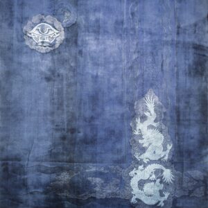 Plush blue rug displaying light gray dragon and cloud motifs with a monogram, laid on wood planks.