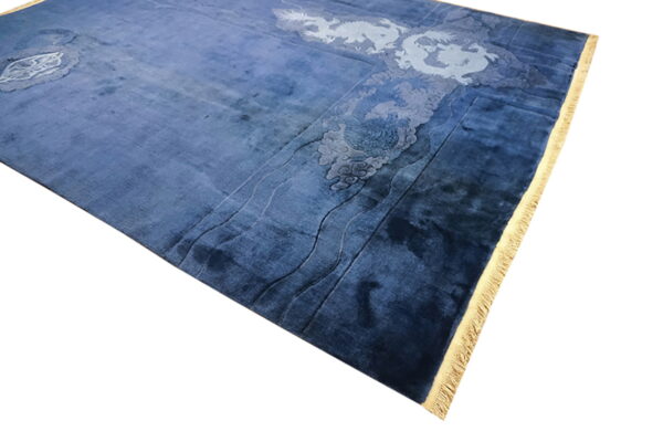 A plush blue rug features lighter blue carved details of dragons, clouds, and waves, with yellow fringe visible.