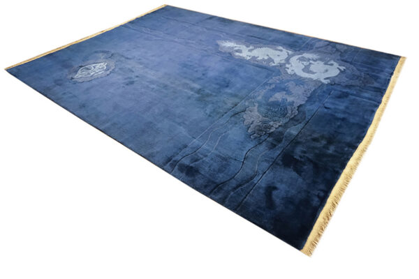 Plush blue rug with large light blue dragon and wave motifs and visible tan fringe.