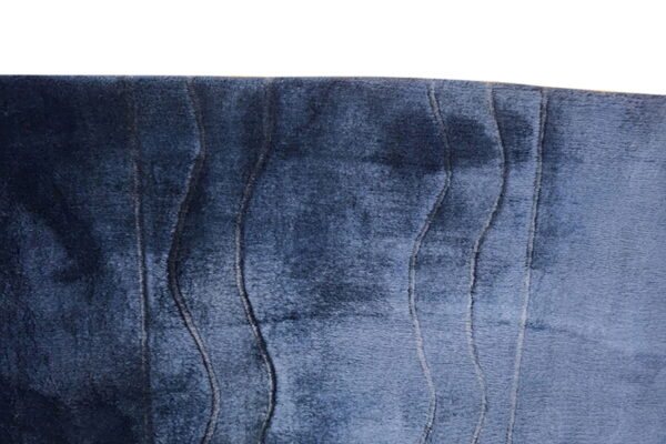 Detail of a dark blue plush rug featuring vertical textured lines creating a wavy pattern.