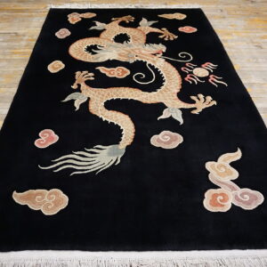 Black rug featuring a large tan dragon and pink clouds on distressed wooden floorboards.