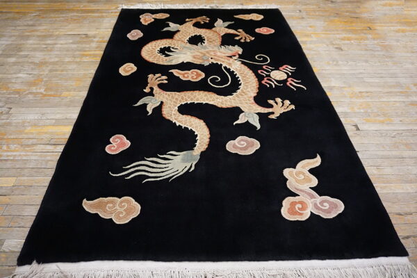 Black rug featuring a large tan dragon and pink clouds on distressed wooden floorboards.
