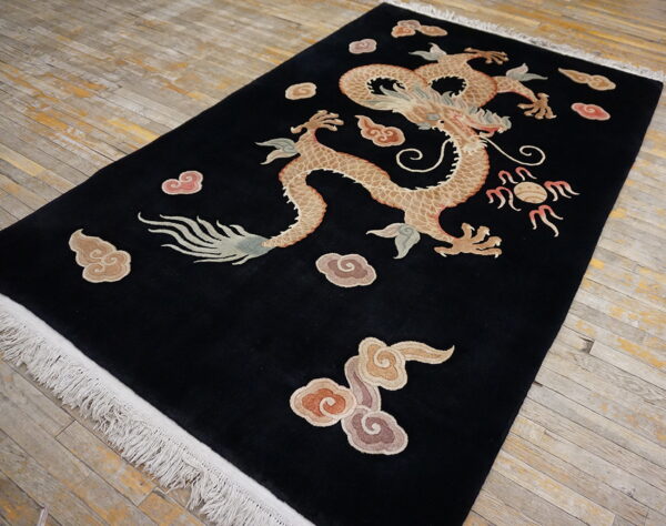 Plush black rug with a central beige dragon and colorful cloud motifs displayed on distressed wood floors.