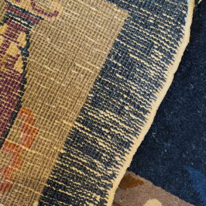Textured loop pile rug featuring geometric patterns overlaps a deep navy blue, high-pile rug.