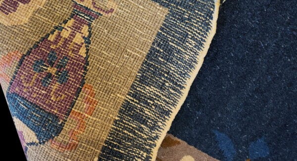 Textured loop pile rug featuring geometric patterns overlaps a deep navy blue, high-pile rug.