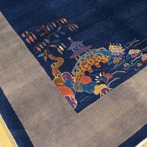 Navy rug with multicolor scenic pattern and wide gray border resting on yellow wood planks.
