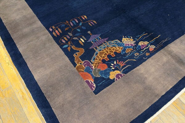 Navy rug with multicolor scenic pattern and wide gray border resting on yellow wood planks.