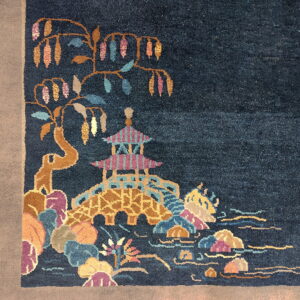 Dark blue rug with a multicolored scene featuring a pagoda, bridge, and floral elements on a light border.