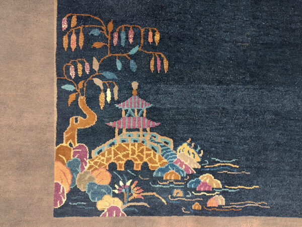 Dark blue rug with a multicolored scene featuring a pagoda, bridge, and floral elements on a light border.