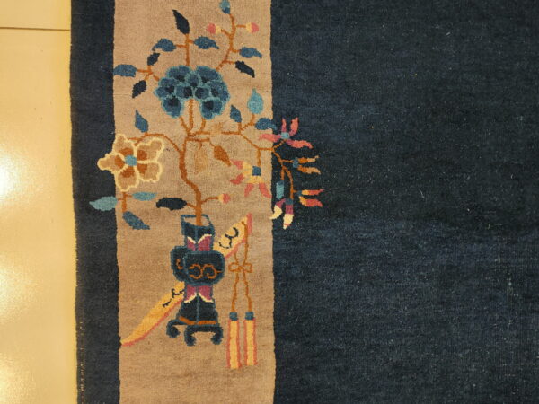 Dark blue rug detail shows a tan border with stylized blue and pink floral designs on a glossy cream floor.