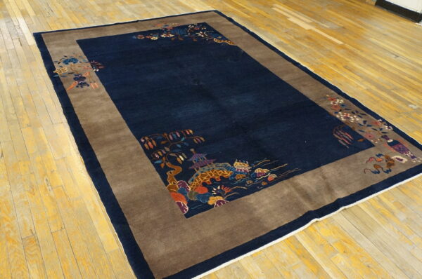 Navy blue rug with a wide brown border featuring detailed multicolored patterns rests on hardwood floors.