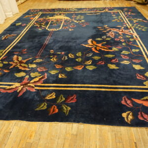 Dark blue plush rug featuring a vibrant floral pattern and gold border on light wood flooring.