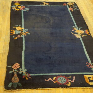 Navy blue rug with a decorative black border and colorful Asian motifs on hardwood flooring.