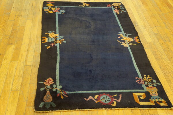 Navy blue rug with a decorative black border and colorful asian motifs on hardwood flooring.