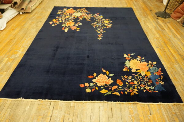 Plush navy rug featuring bright yellow and orange floral patterns, laid on yellow hardwood.